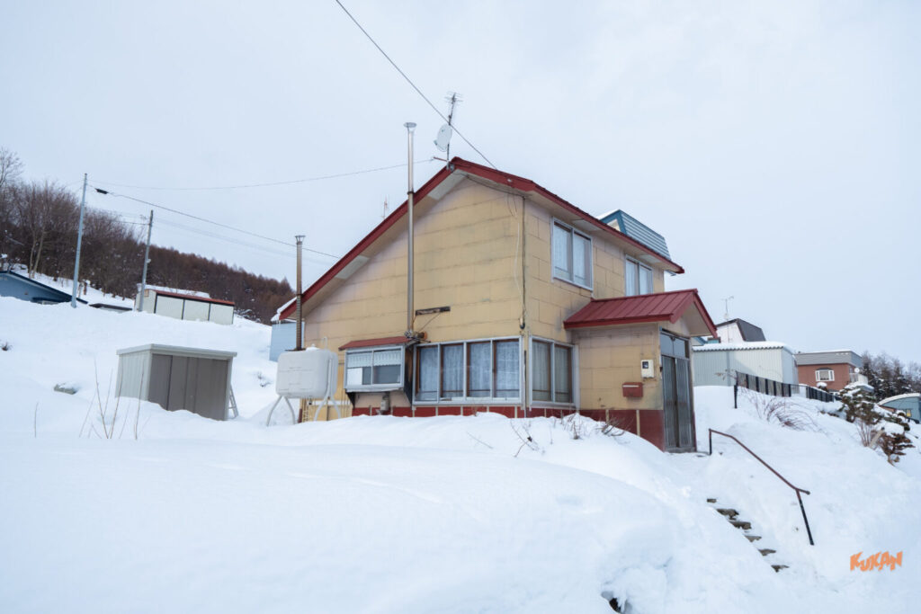 中富良野の不動産投資や別荘に最適な、雪景色の角地に建つ2階建て中古戸建て物件の外観