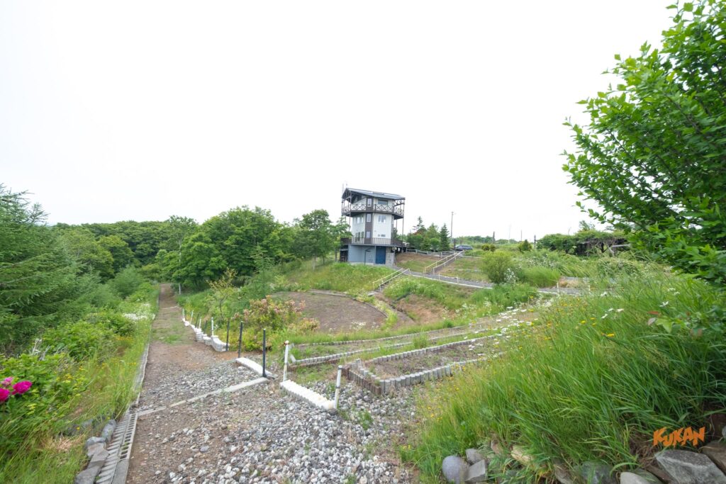 石狩市望来の大自然に囲まれた丘の上に建つサマーロッジと、手前に広がる整備された段々畑。