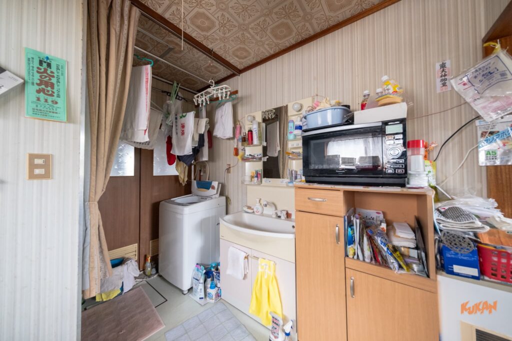 富良野北の峰にある投資用角地戸建ての洗面所と脱衣所。洗面台や洗濯機を備えた生活感のある内観。