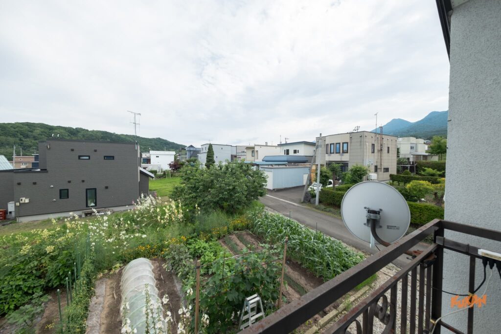 富良野北の峰にある投資用角地戸建てのバルコニーからの眺望。手前に広がる菜園と静かな住宅街。