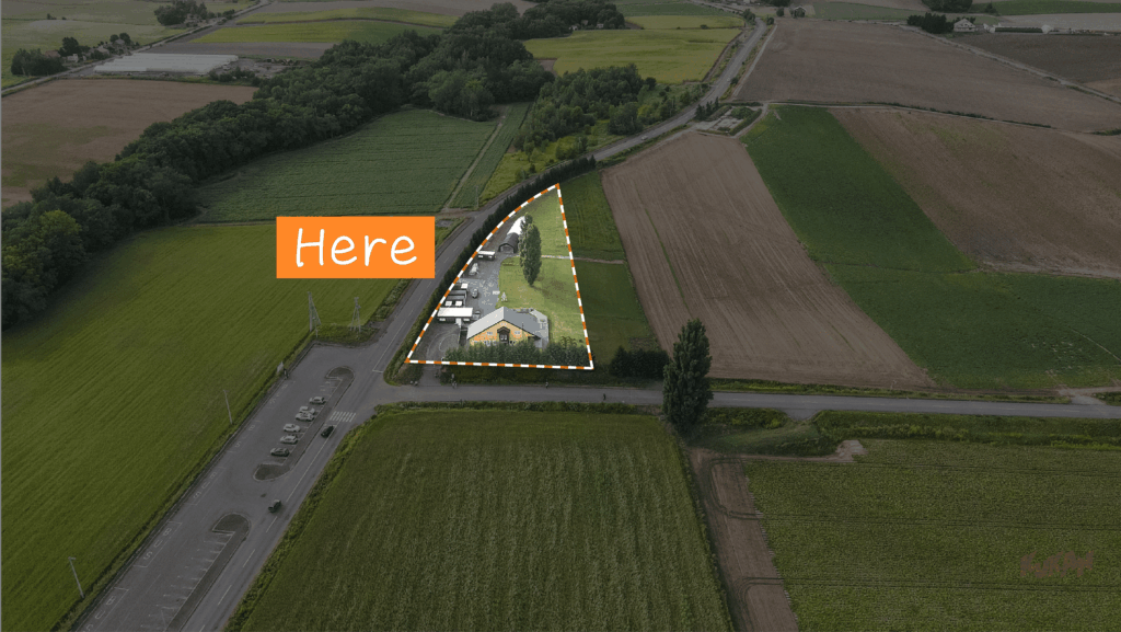 ケンとメリーの木に隣接する美瑛町の広大なリゾート開発用地と黄色い建物の空撮風景。