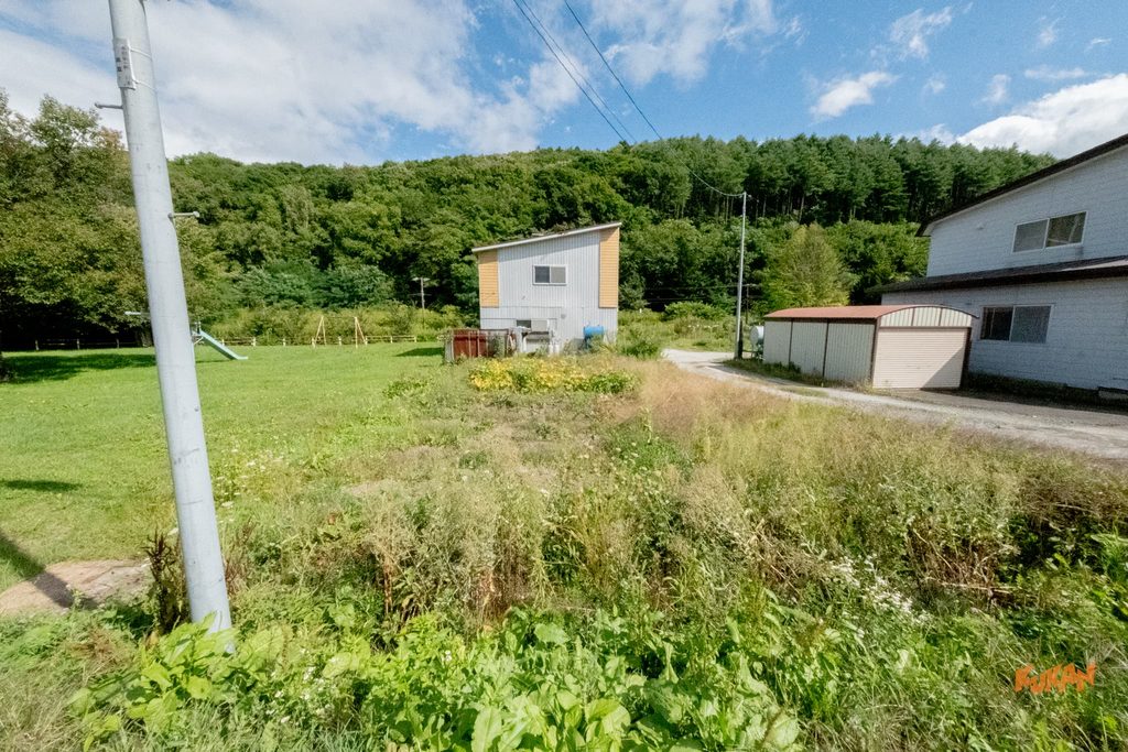 富良野市布部にある緑豊かな自然に囲まれた広い土地と中古戸建ての外観