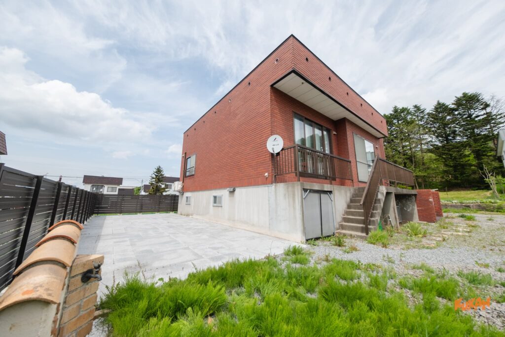 旭川の一棟貸し民泊物件のバルコニーと敷地内タイルスペースがある建物外観