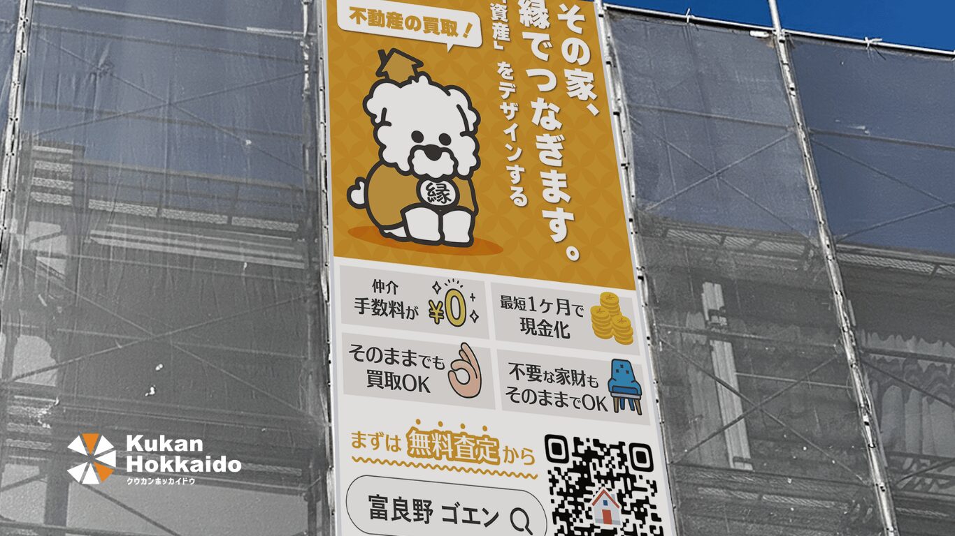 クウカン株式会社による現場シートデザイン事例。富良野の不動産買取専門店「ゴエン」の足場シート。かわいい犬キャラクターとオレンジ色を基調に、仲介手数料0円・そのまま買取OKなどのメッセージを掲載したデザイン。