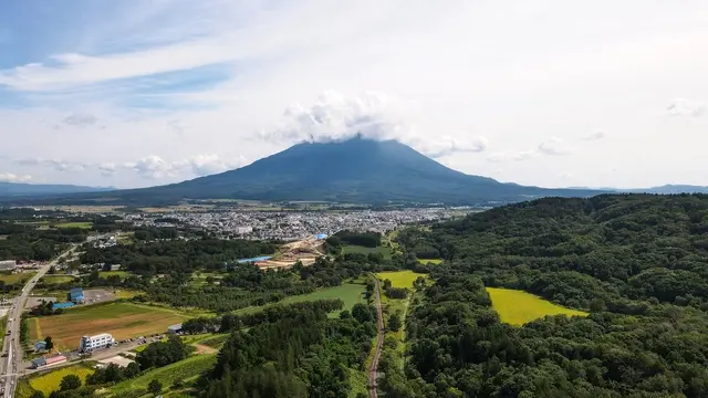 晴空下綠意盎然的北海道富良野廣闊土地與城鎮全景（「GOEN不動產收購專門店」協助閒置空屋與土地高價出售）