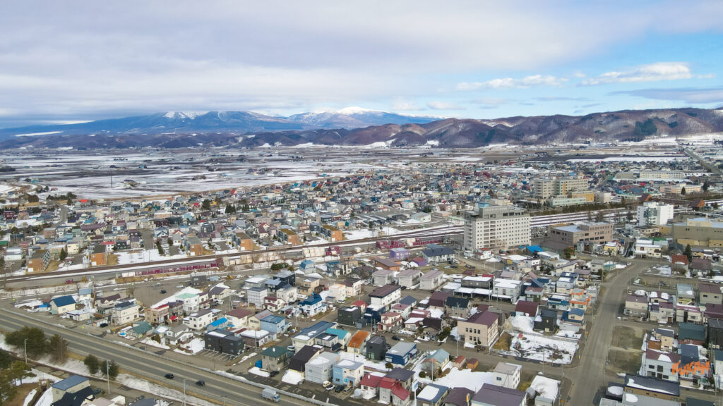雪が残る富良野・美瑛・倶知安エリアの街並みと山々を俯瞰した開発・別荘管理地景観