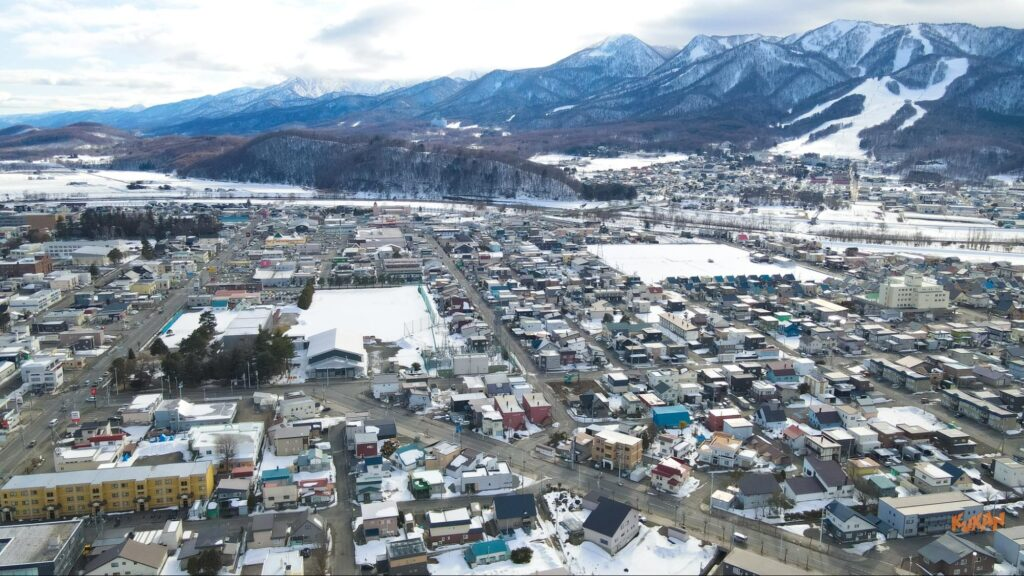 一棟貸し民泊「Shikauchi」が位置する雪景色に包まれた北海道中富良野の街並みと雄大な山々