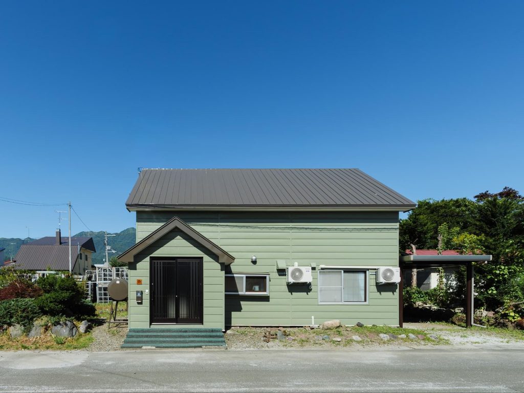 富良野市山部に位置するフルリノベ一棟貸し民泊『YAM-PE』の緑豊かな建物外観