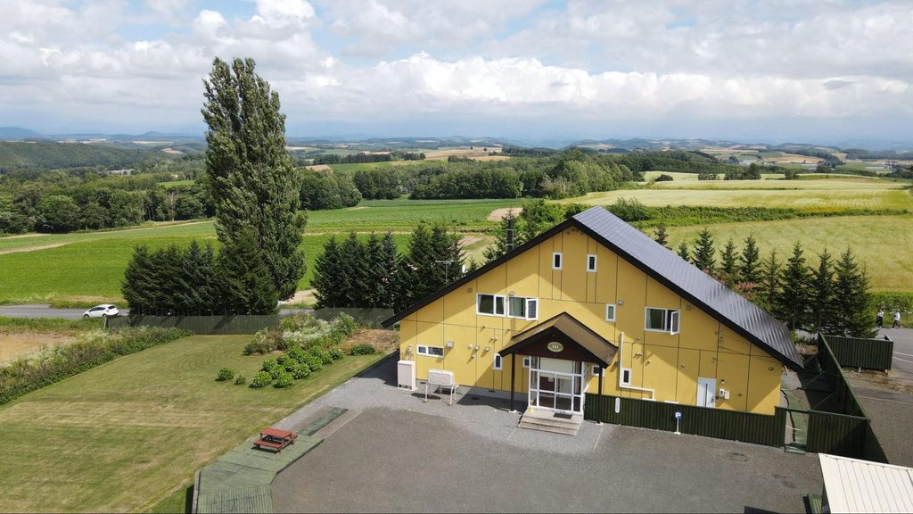 Yellow building and resort development land for sale adjacent to Biei's Ken and Mary Tree in Hokkaido